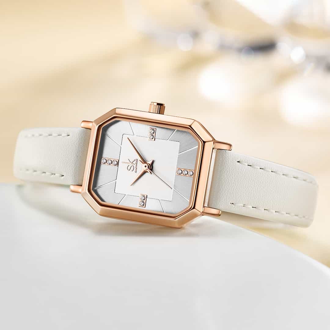 Orologio donna SK Shengke Chic White su sfondo decorativo - posizione sdraiata.